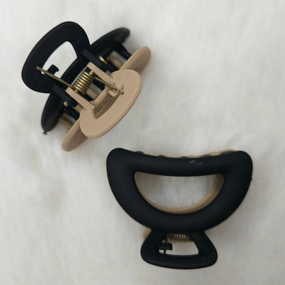 Two hair clips, one black and one beige, on a white background