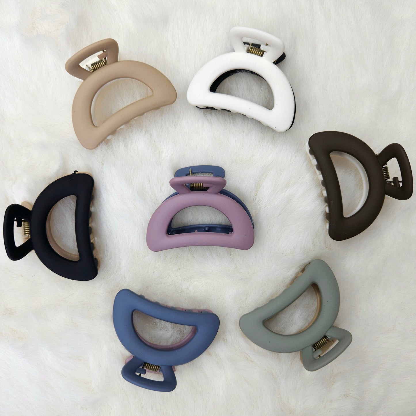 Set of eight semi circle shaped hair claw clips in various colors on a white background