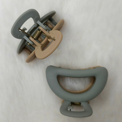 Two hair clips, one gray and one beige, on a white background