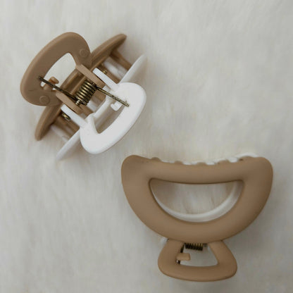 Two brown hair clips on a white textured background