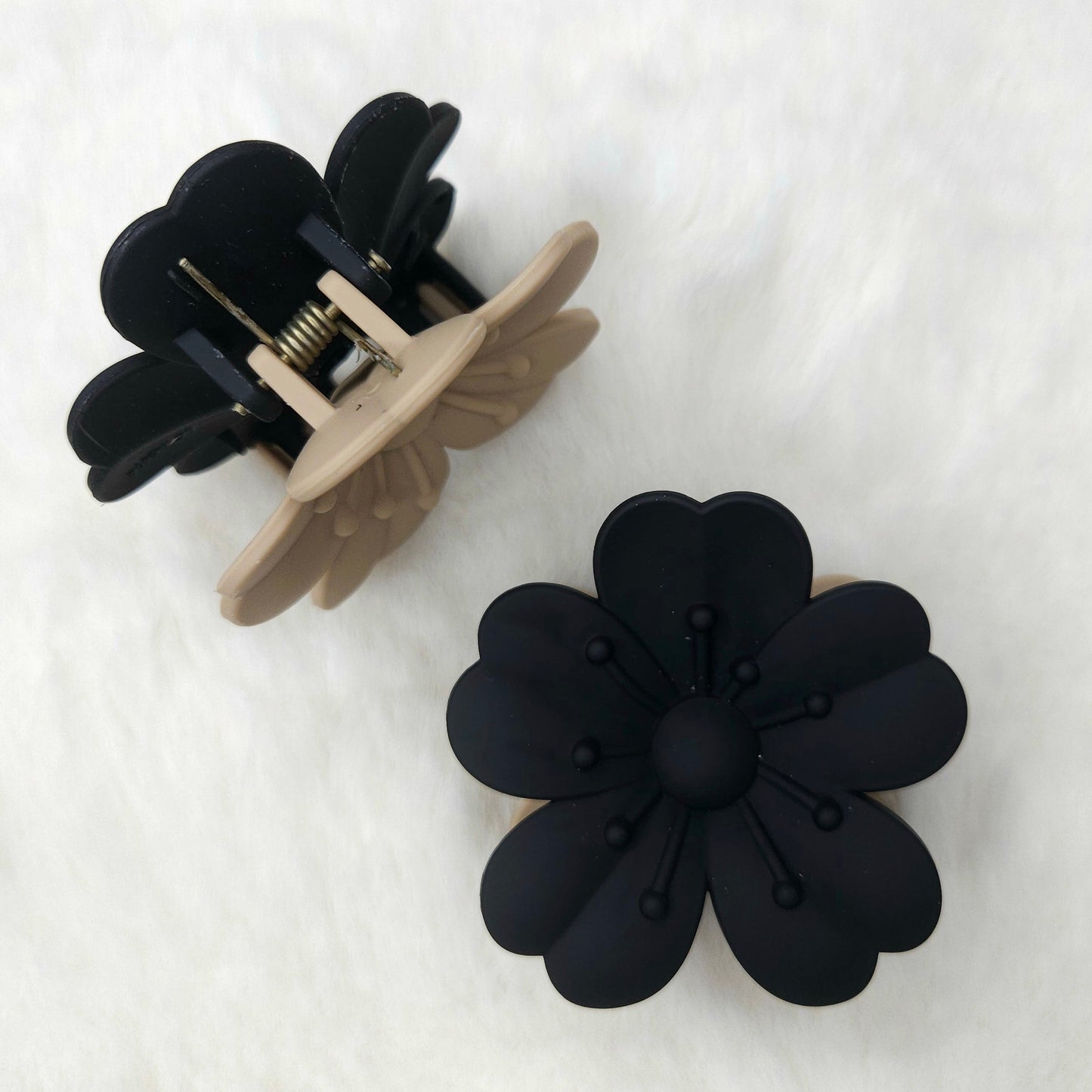 Black flower-shaped hair clip on a white background