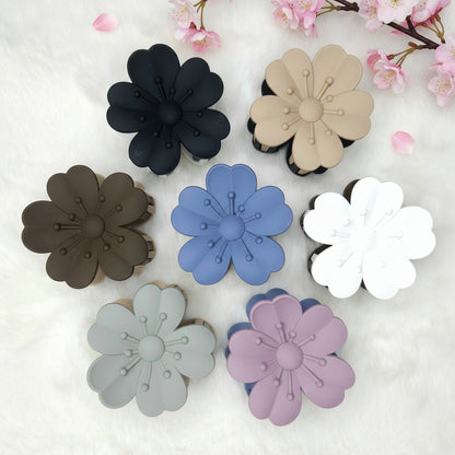 Set of flower-shaped hair claw clips in various colors on a white background with cherry blossoms.