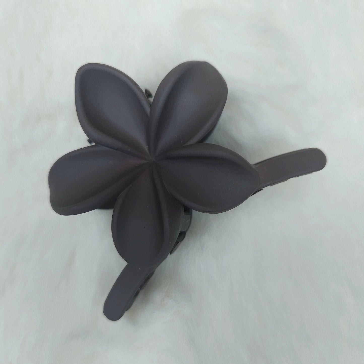 Black flower-shaped hair clip on a white background