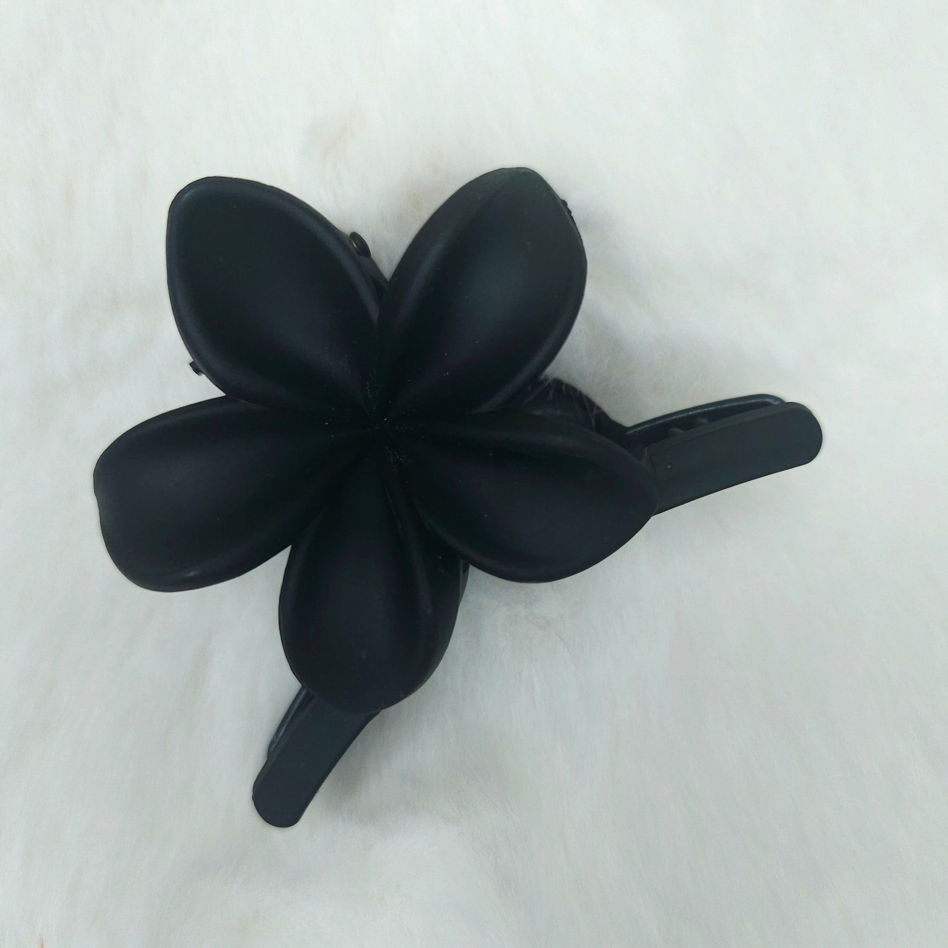 Black flower-shaped hair clip on a white background