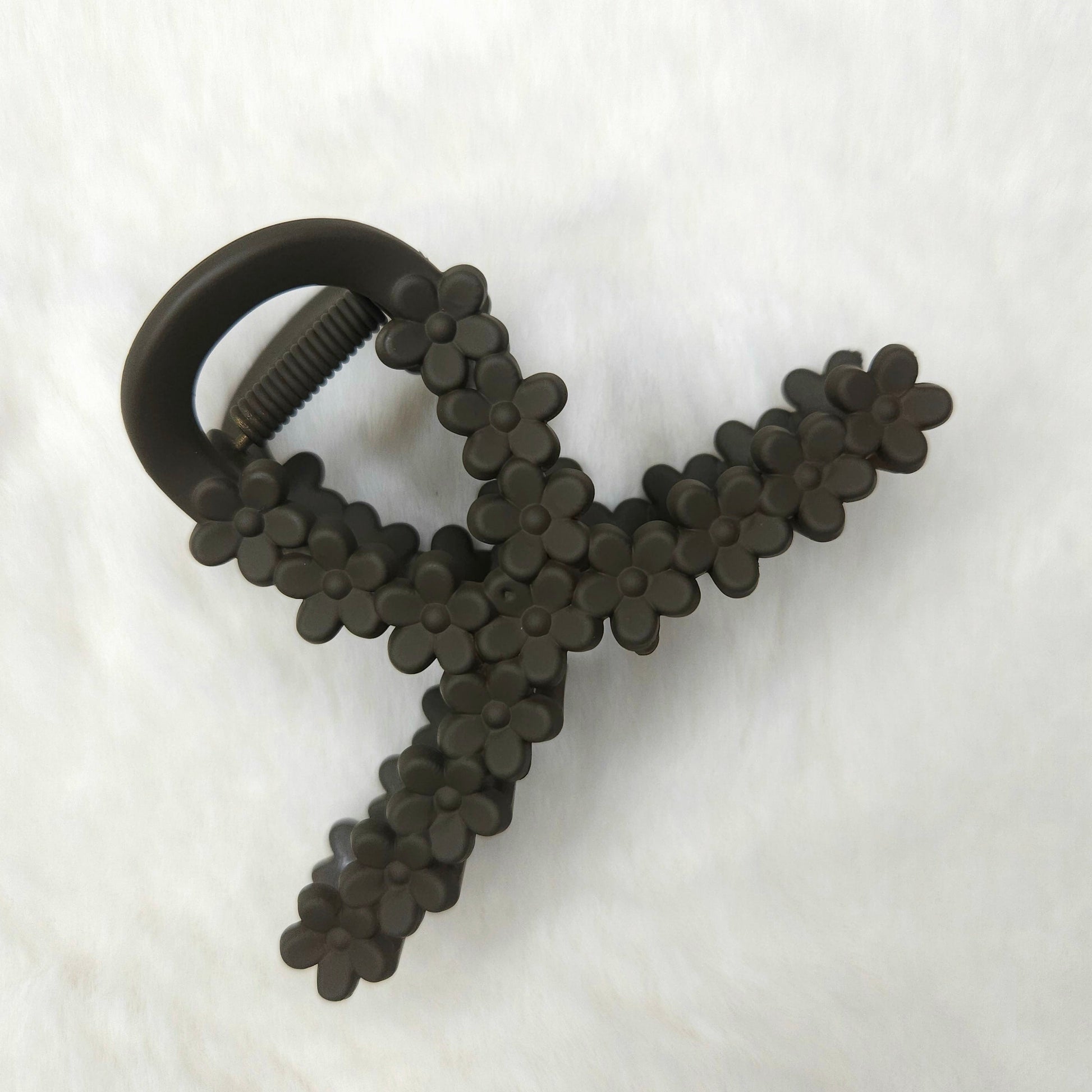 Loop shaped brown color hair claw clip with flow details placed on a white background.