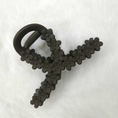 Loop shaped brown color hair claw clip with flow details placed on a white background.