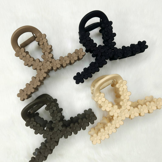 Four hair claw clips in black, brown, and beige on a white background