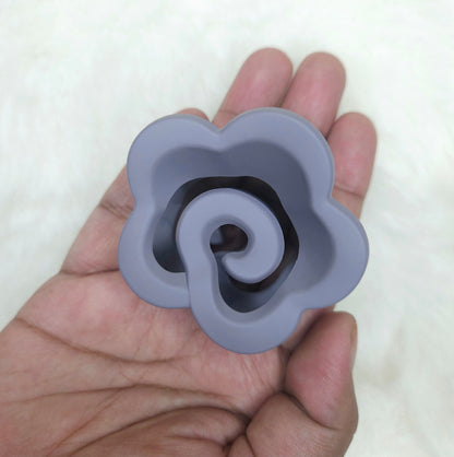 Gray silicone flower-shaped hair claw held in a hand against a white background