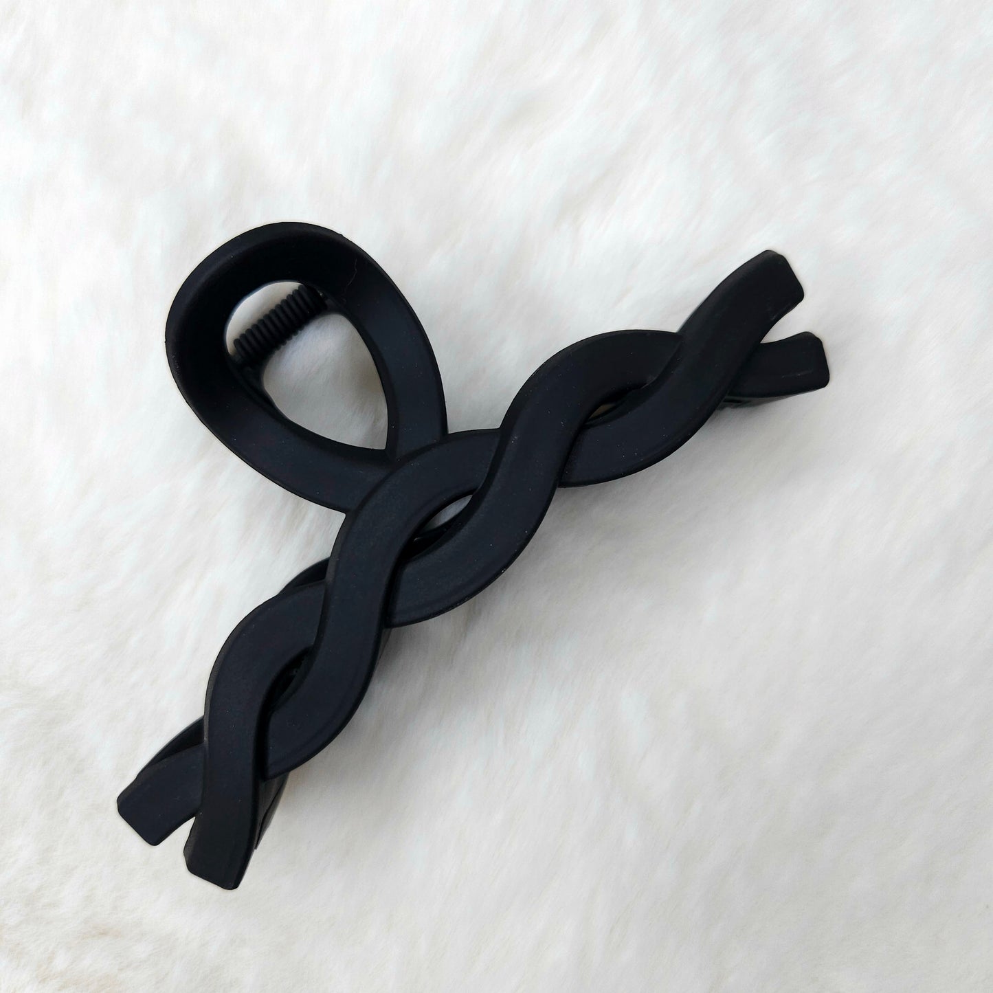 Black color hair claw clip on a white textured surface