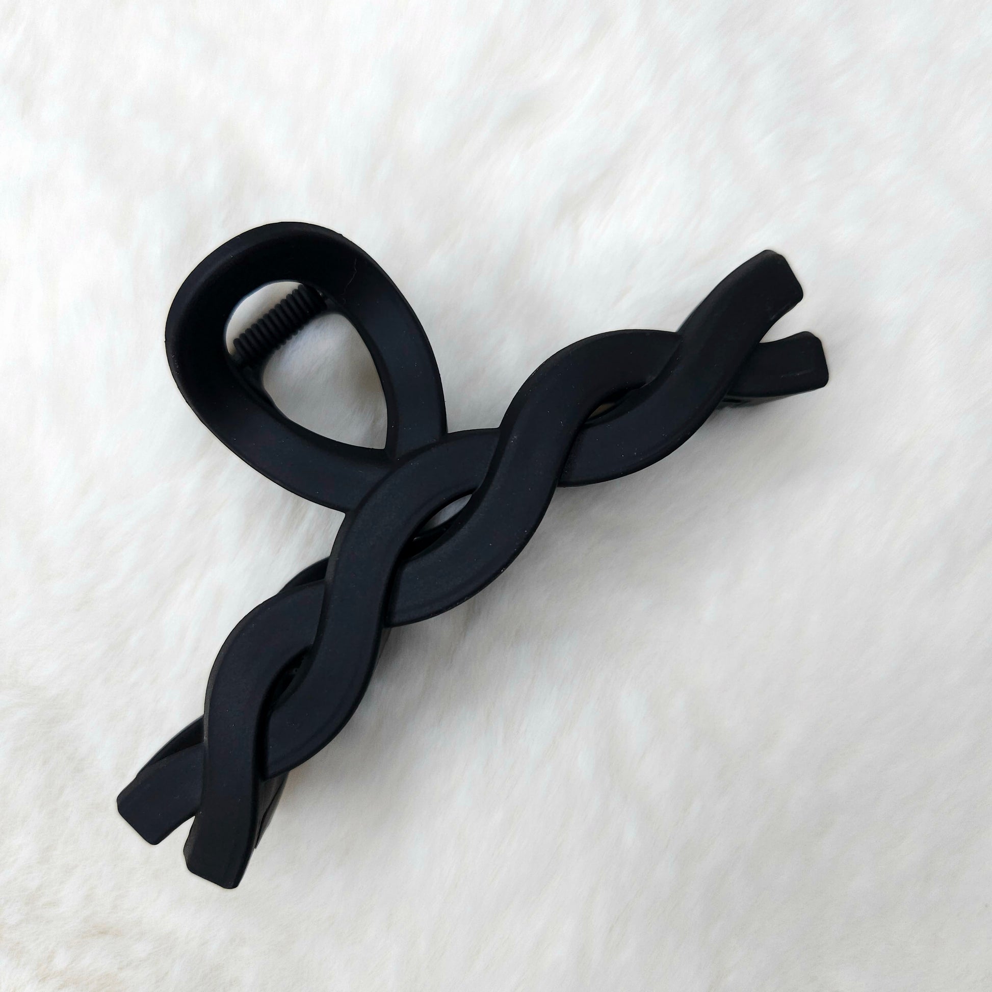Black color hair claw clip on a white textured surface