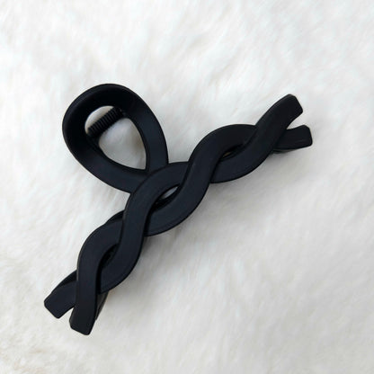 Black color hair claw clip on a white textured surface