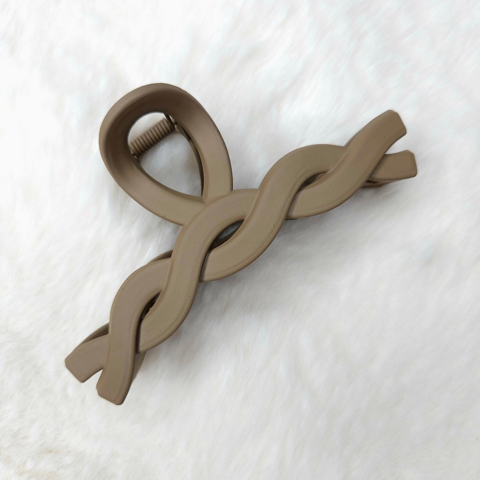 Brown twisted design hair claw clip on a white textured background