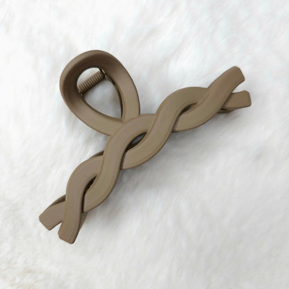 Brown twisted design hair claw clip on a white textured background