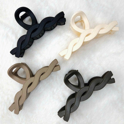 Four hair clips in black, beige, and white on a textured white background