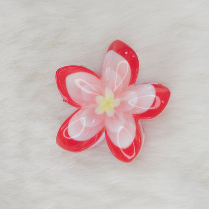 An orange and white translucent plastic flower-shaped hair clip with a light blue center, seen from above.