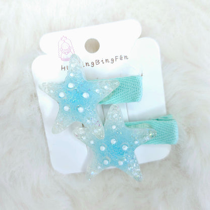 Pair of blue star-shaped hair clips on a white card with 'Hi Bingfen' branding, on a white fluffy background.