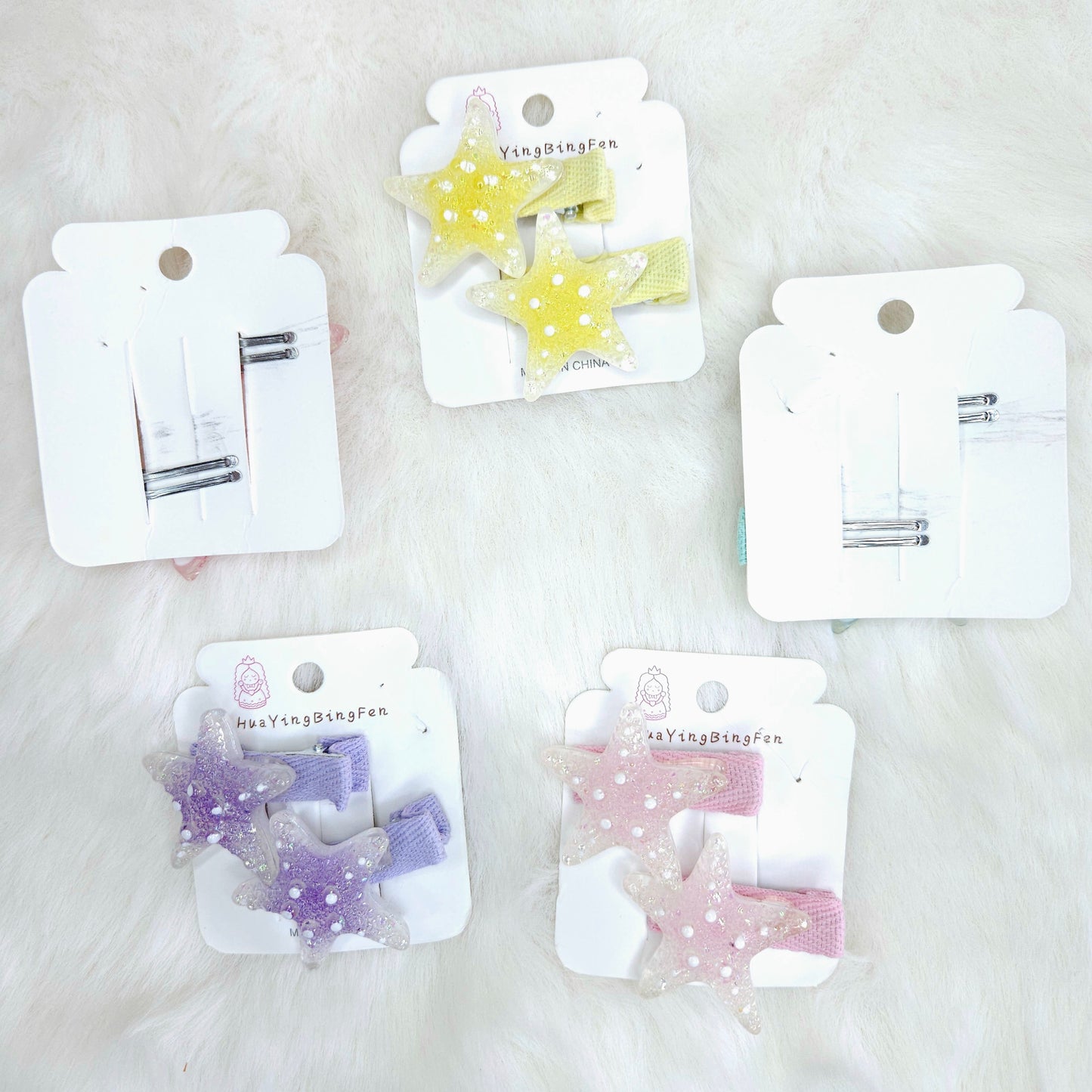 Set of star-shaped hair clips on white cards with visible brand name on a light background
