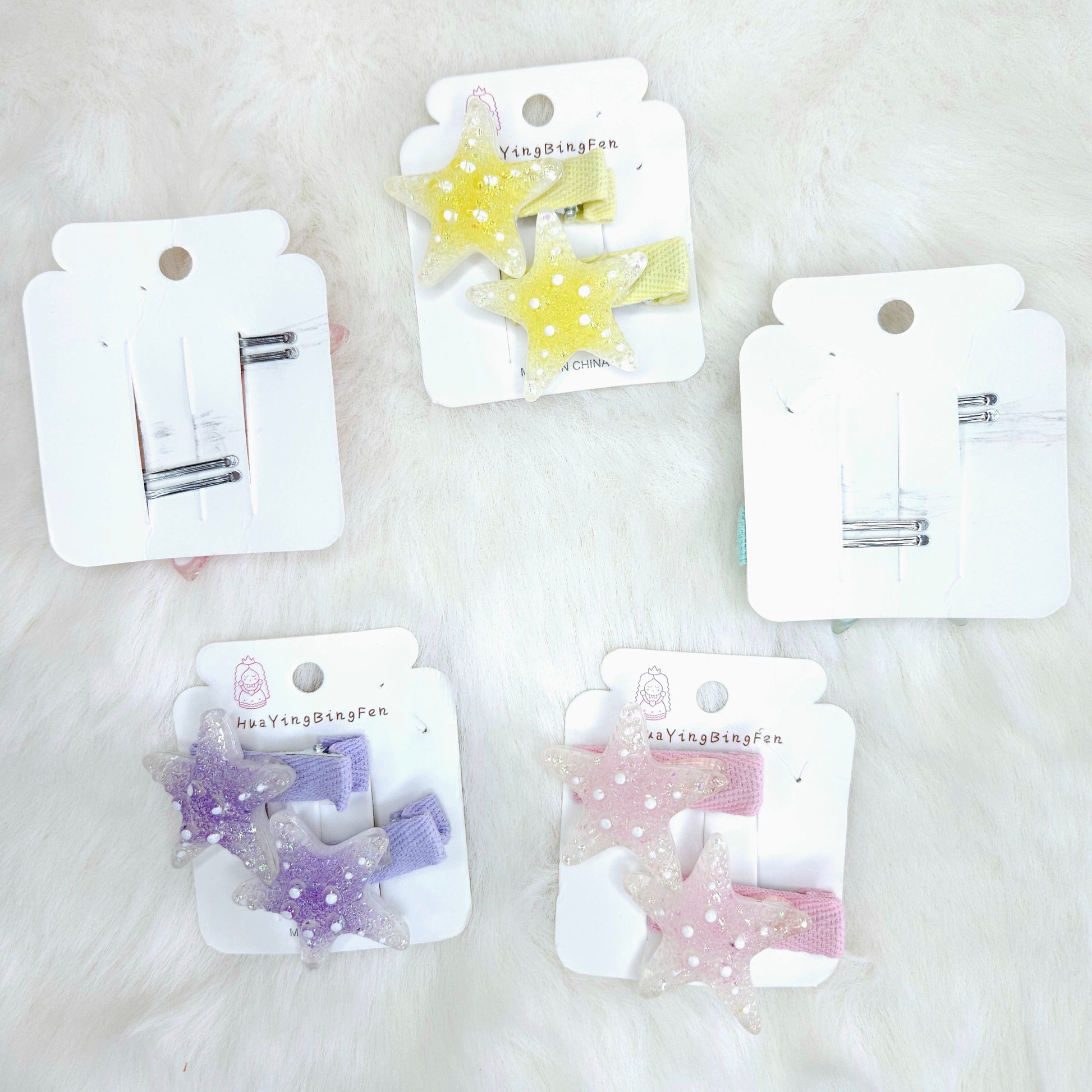 Set of star-shaped hair clips on white cards with visible brand name on a light background