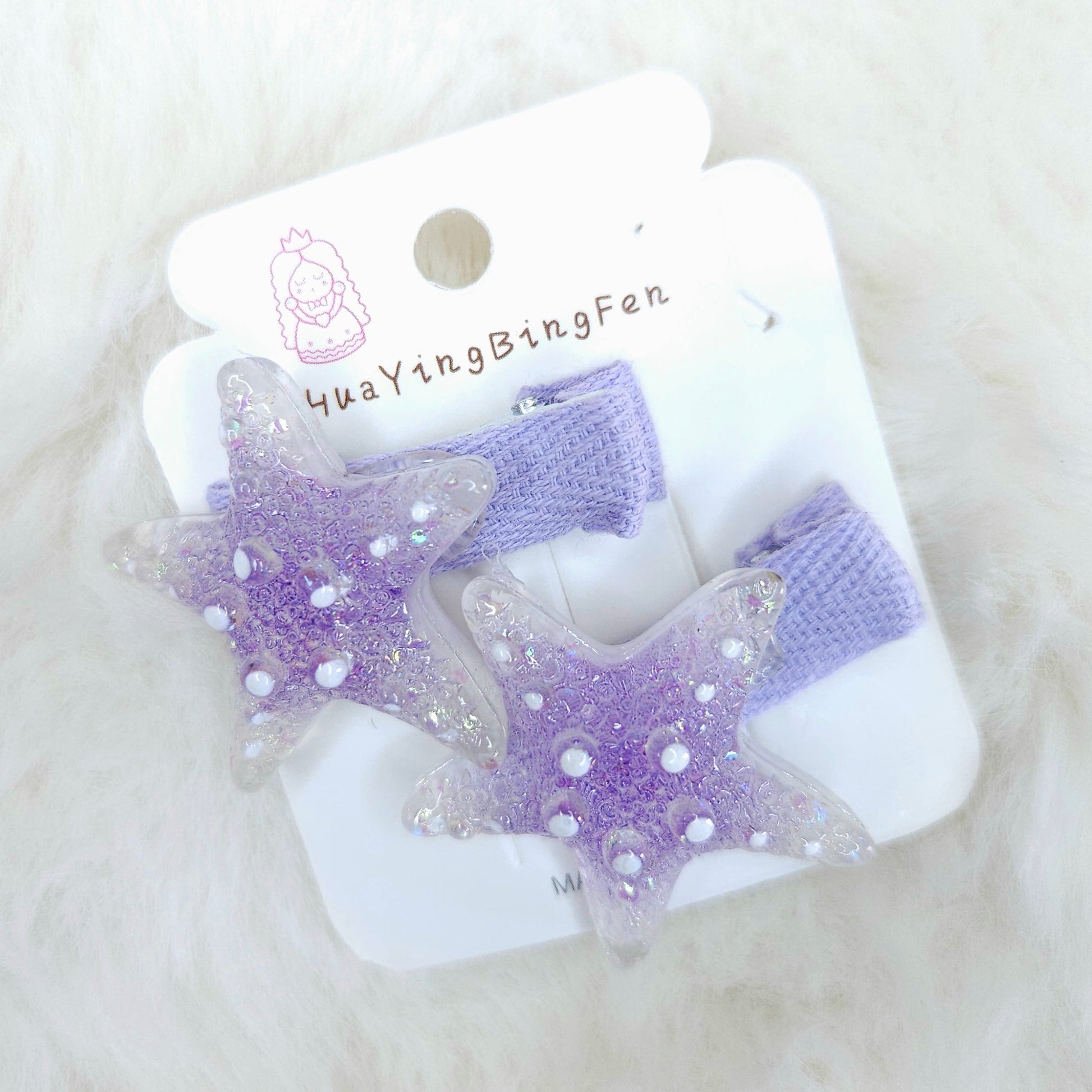 Purple star-shaped hair clips on a white card with 'YuaYingBingFen' branding on a white fluffy background.