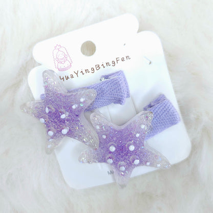 Purple star-shaped hair clips on a white card with 'YuaYingBingFen' branding on a white fluffy background.