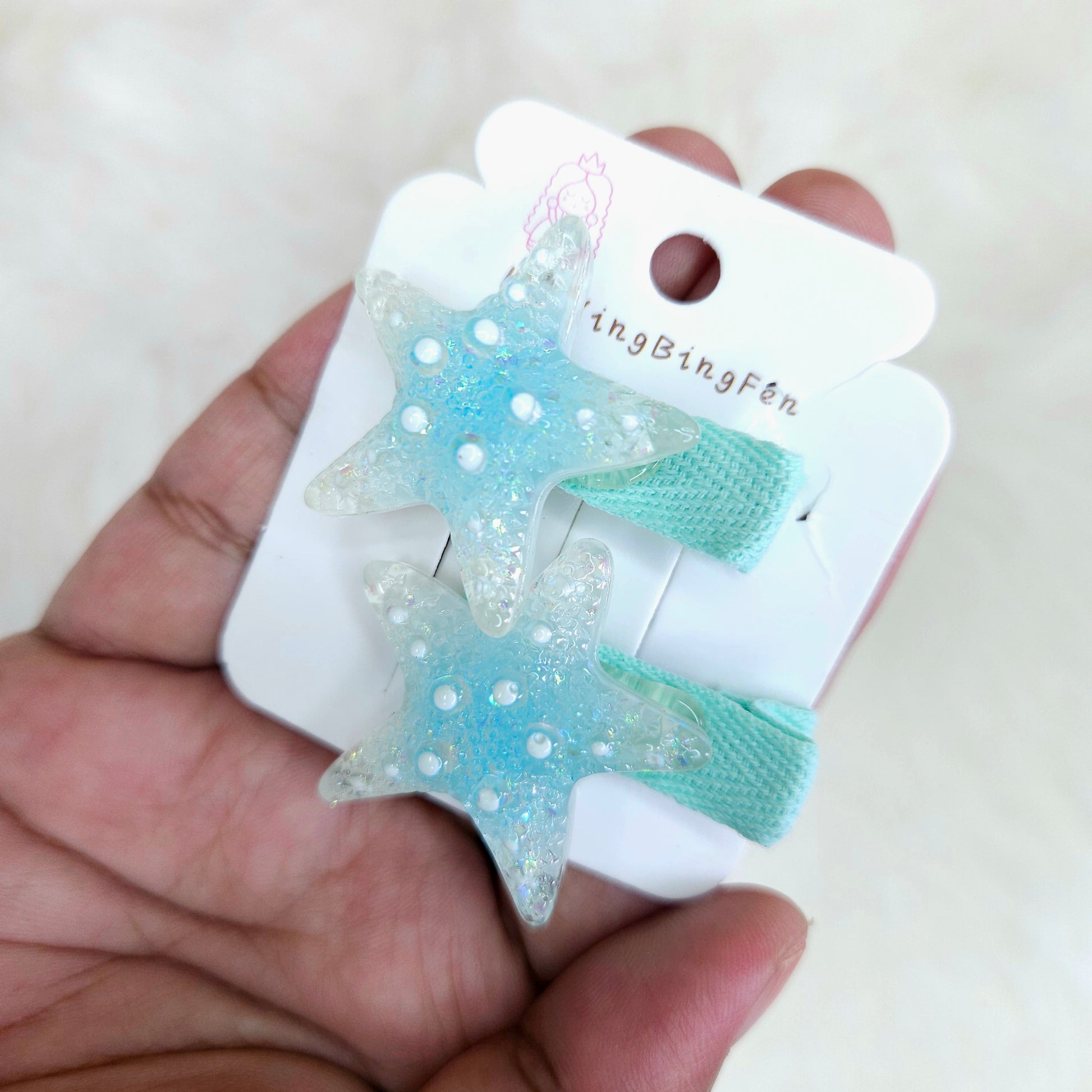 Star-shaped hair clips on a card held by a hand with a white background