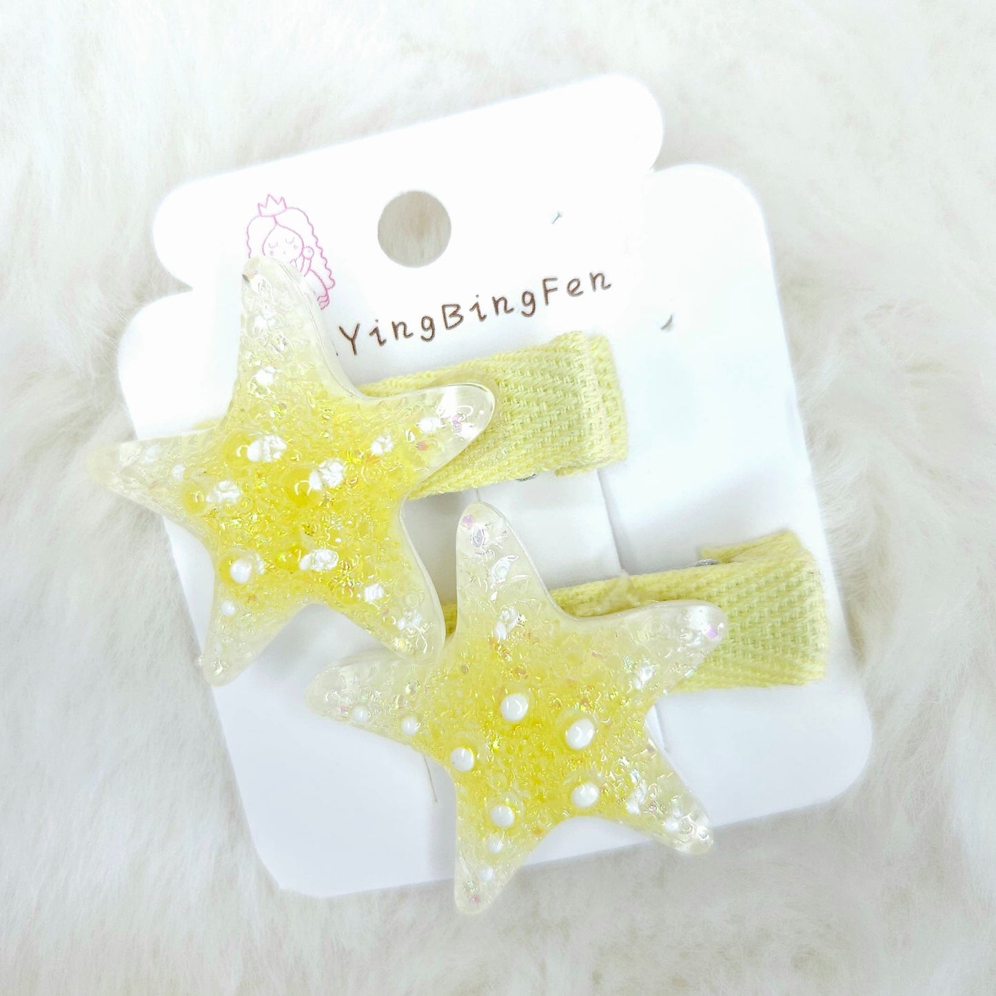 Star-shaped hair clips on a white card with 'YingBingFen' branding, placed on a white fluffy surface.