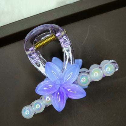Clear hair claw with a turquoise blue flower and a row of small, clear iridescent pearl embellishments.