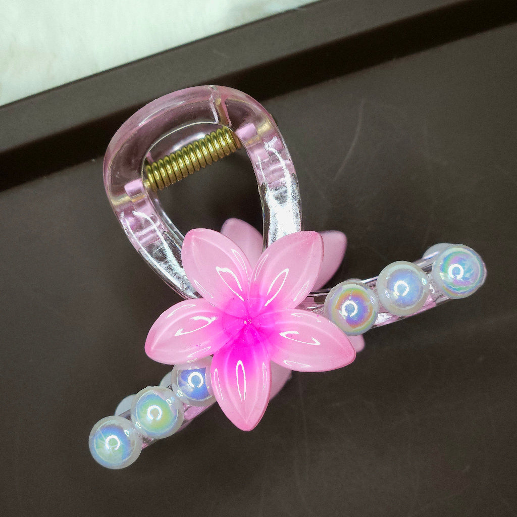 Clear mini hair claw clip featuring a bright pink flower and a curved line of white bubble pearls.
