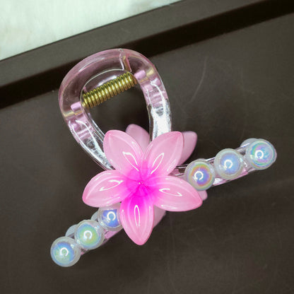 Clear mini hair claw clip featuring a bright pink flower and a curved line of white bubble pearls.