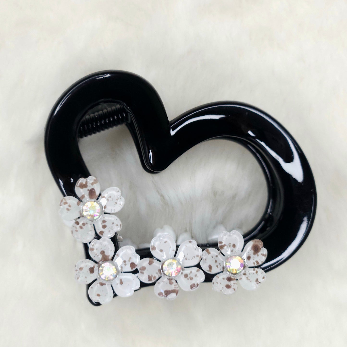 Black heart-shaped hair clip with floral decorations on a white background
