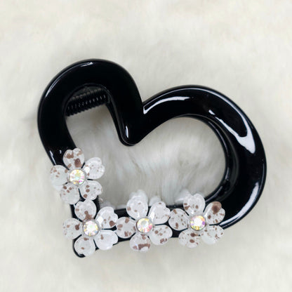 Black heart-shaped hair clip with floral decorations on a white background