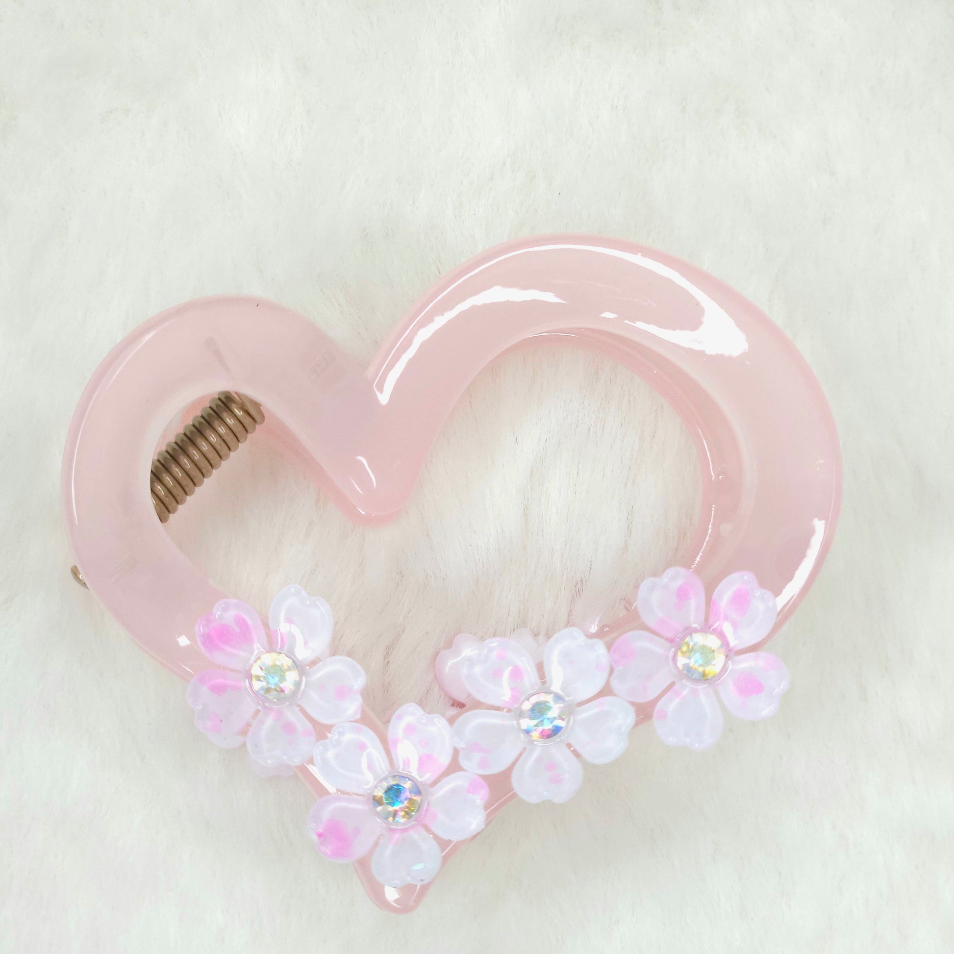Pink heart-shaped hair clip with floral decorations on a white background