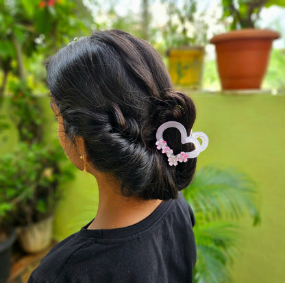 Person with a hair bun holding a decorative hair clip outdoors
