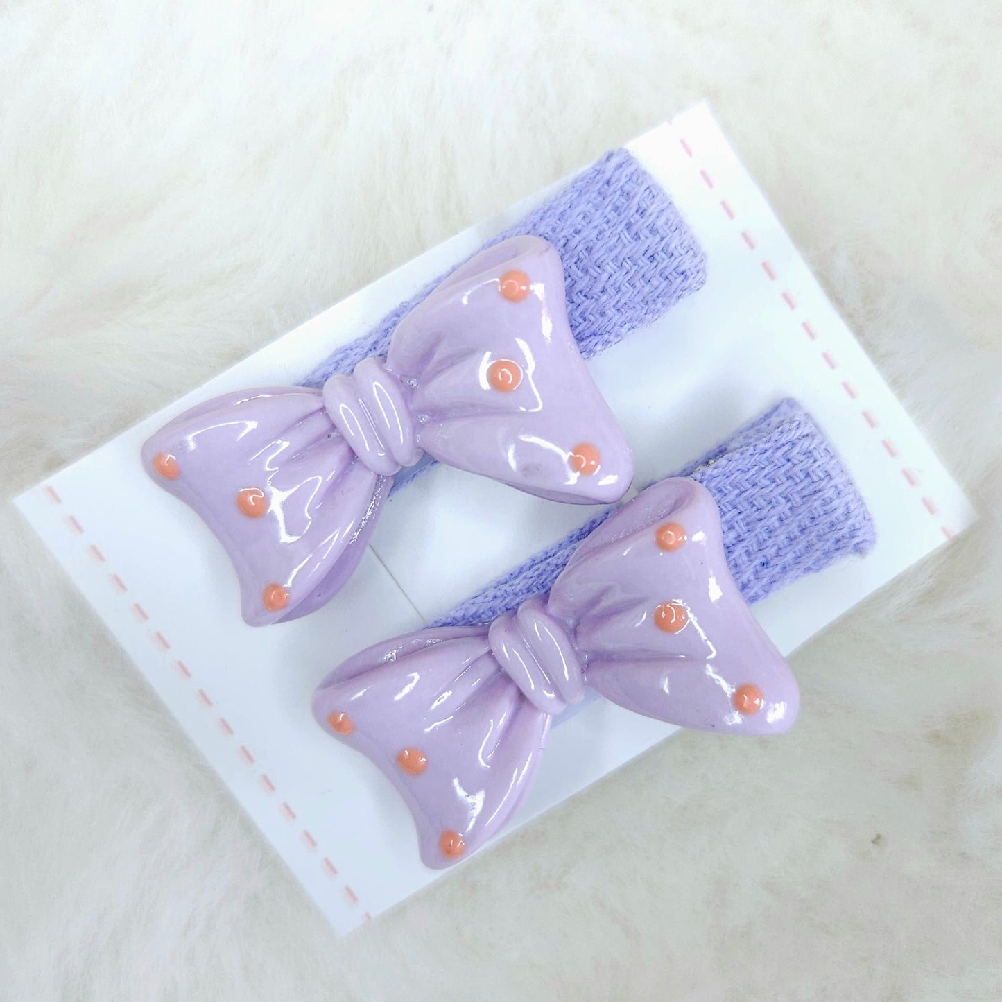 Pair of purple hair bows with gold accents on a white background