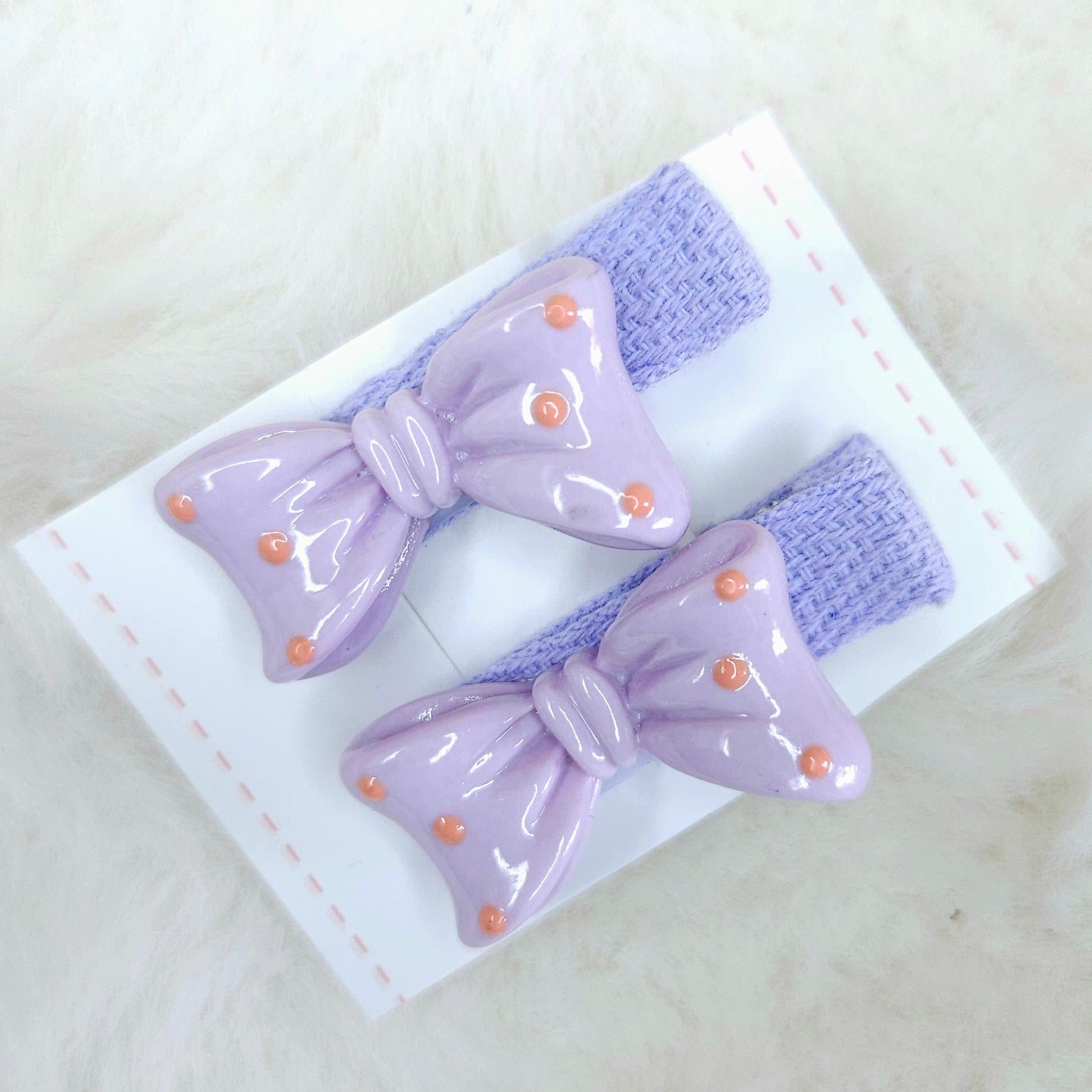 Pair of purple hair bows with gold accents on a white background