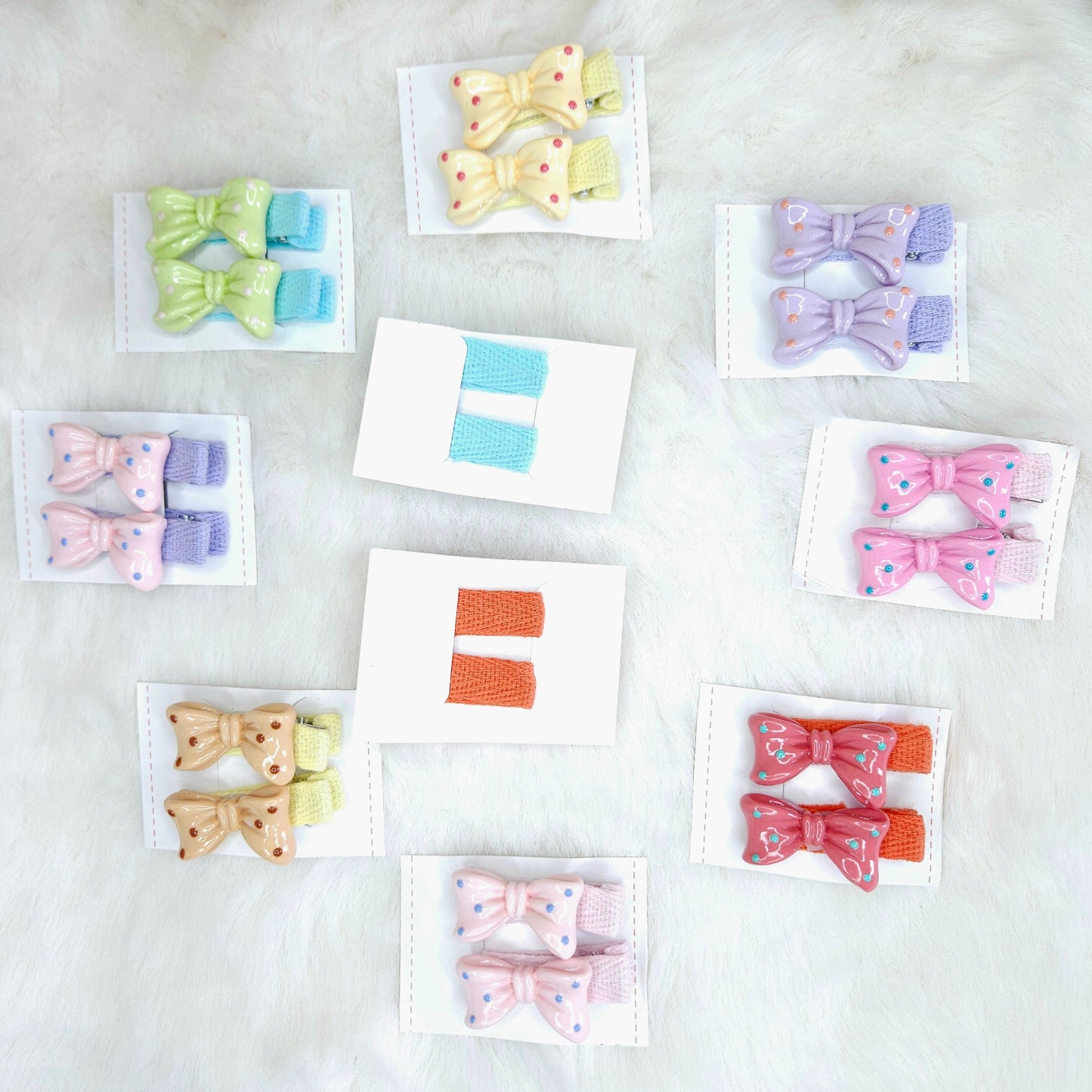 Collection of colorful hair bow clips on small cards against a light background