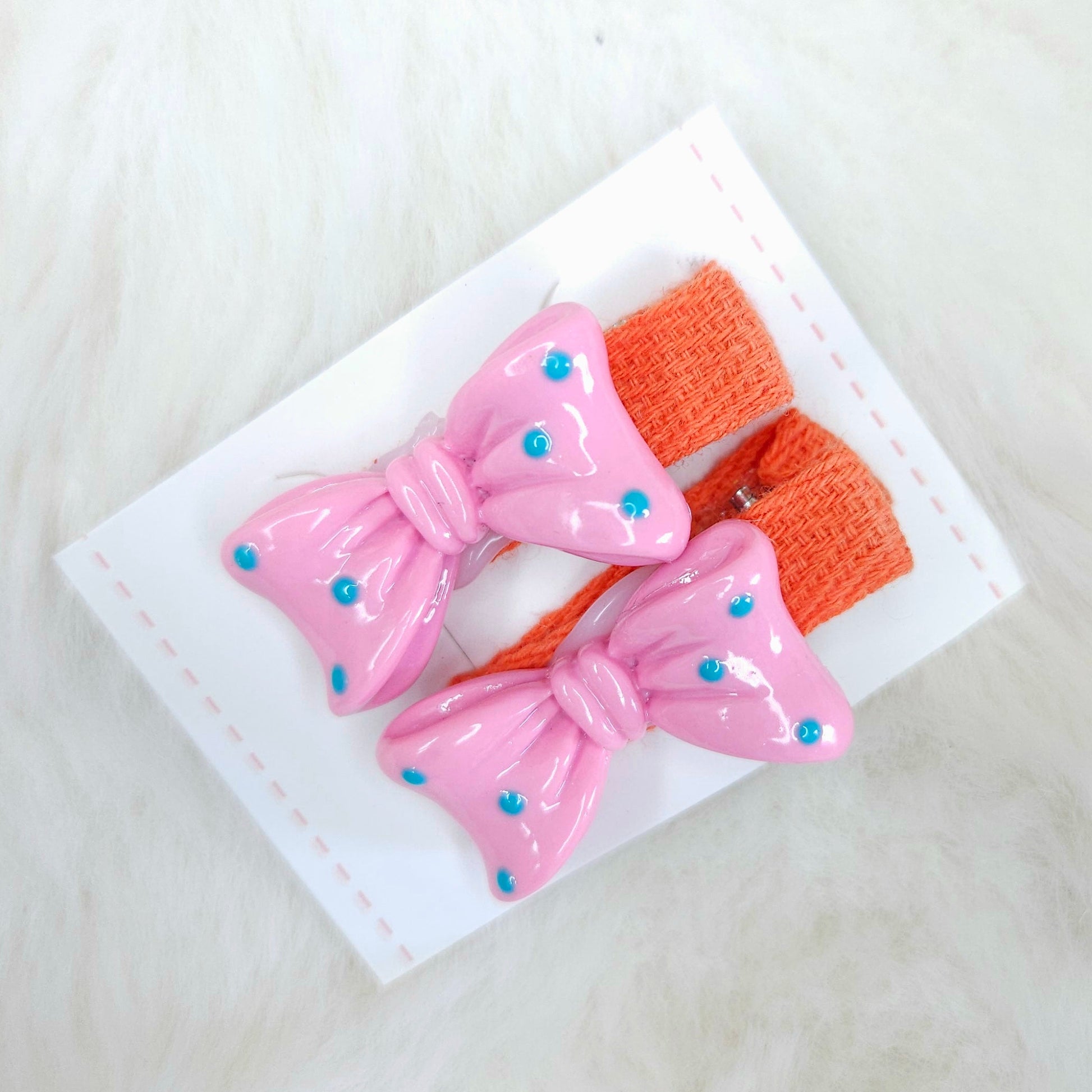 Pink hair bow clips with orange accents on a white background