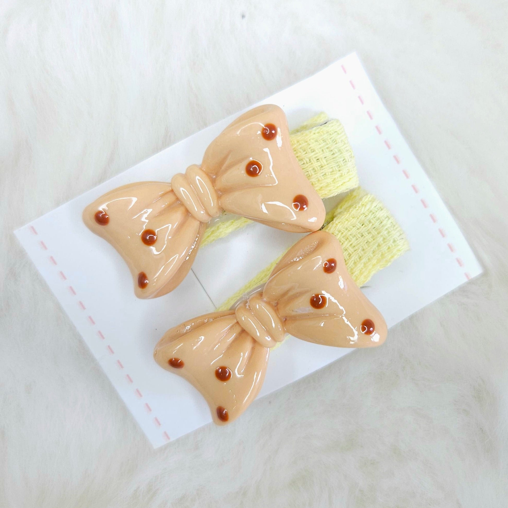 Two bow-shaped hair clips on a white card with a light background