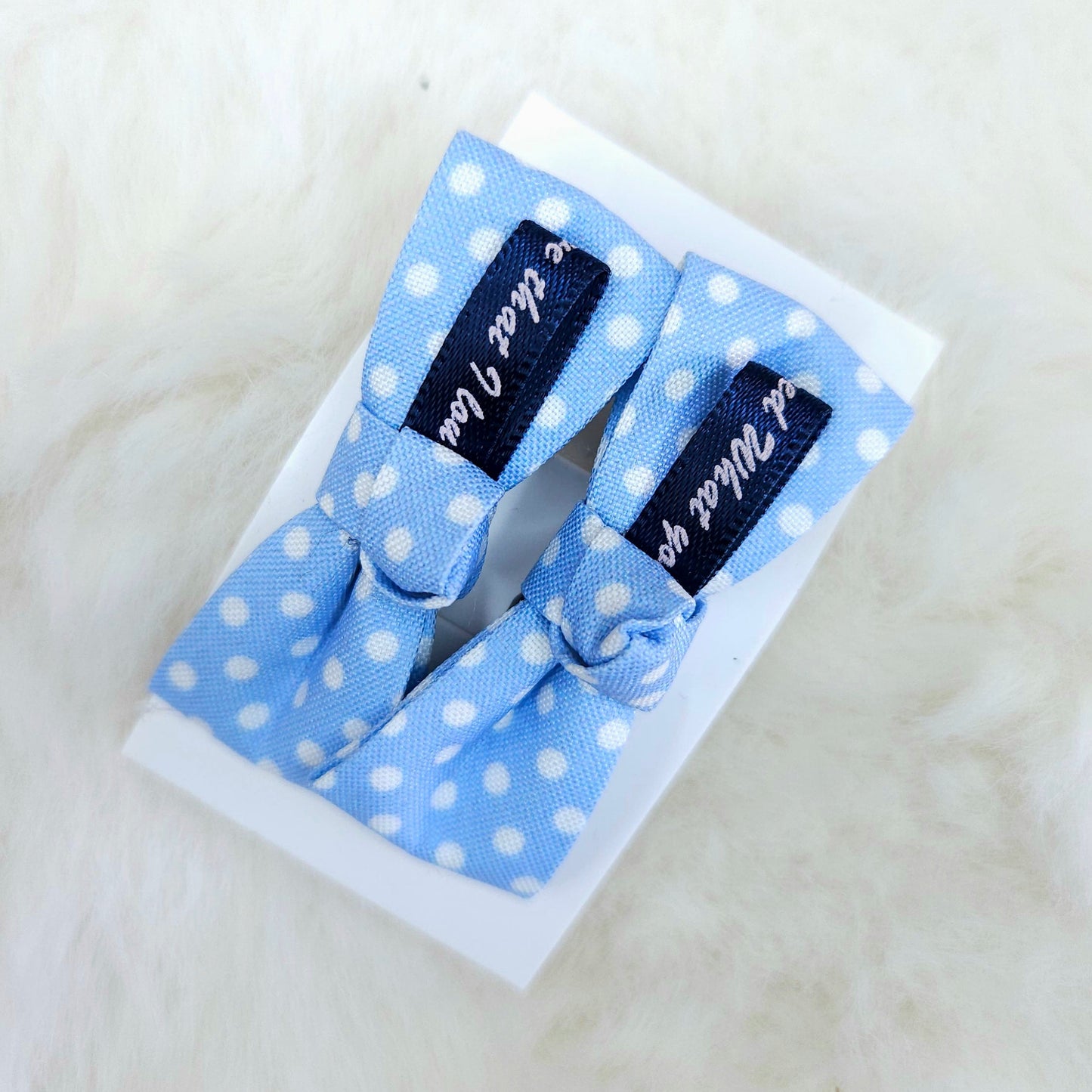Set of blue polka dot hair bows with black ribbons on a white background