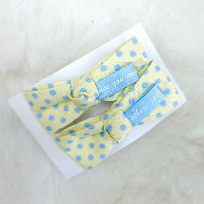 Yellow polka dot bow tie with blue labels on a white background