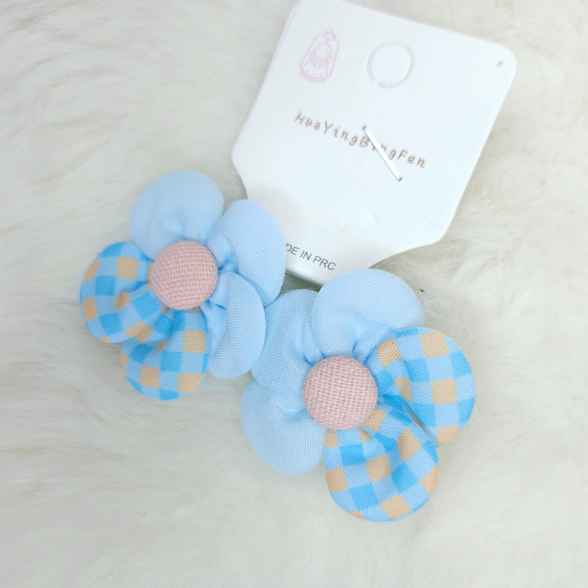Pair of blue checkered flower-shaped hair clips with pink centers on a white background.