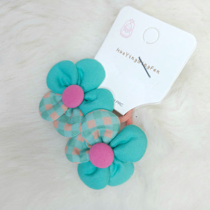 Turquoise flower-shaped hair clips with pink centers on a white background