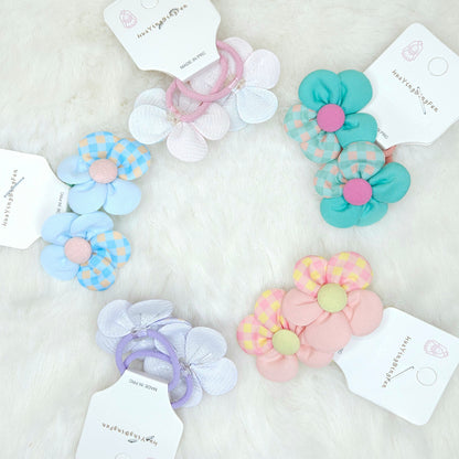 Set of colorful flower-shaped hair ties with matching packaging on a light background