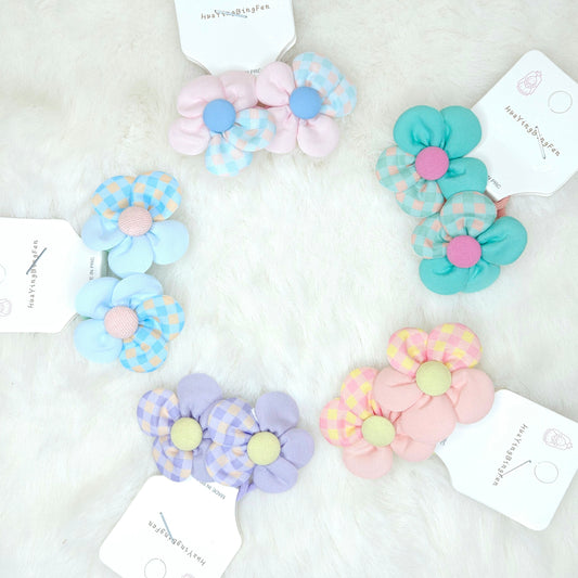 Set of colorful flower-shaped hair ties on a white background with brand tags.