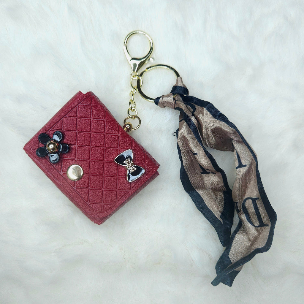 Elegant Red Quilted Leatherette Key Fob with detailed diamond stitching. The accessory is styled with a chic black and tan patterned ribbon scarf and shiny enamel embellishments.