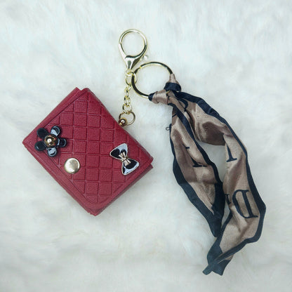 Elegant Red Quilted Leatherette Key Fob with detailed diamond stitching. The accessory is styled with a chic black and tan patterned ribbon scarf and shiny enamel embellishments.