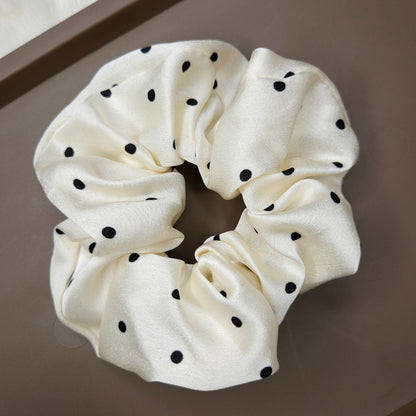 White scrunchie with black polka dots on a brown surface