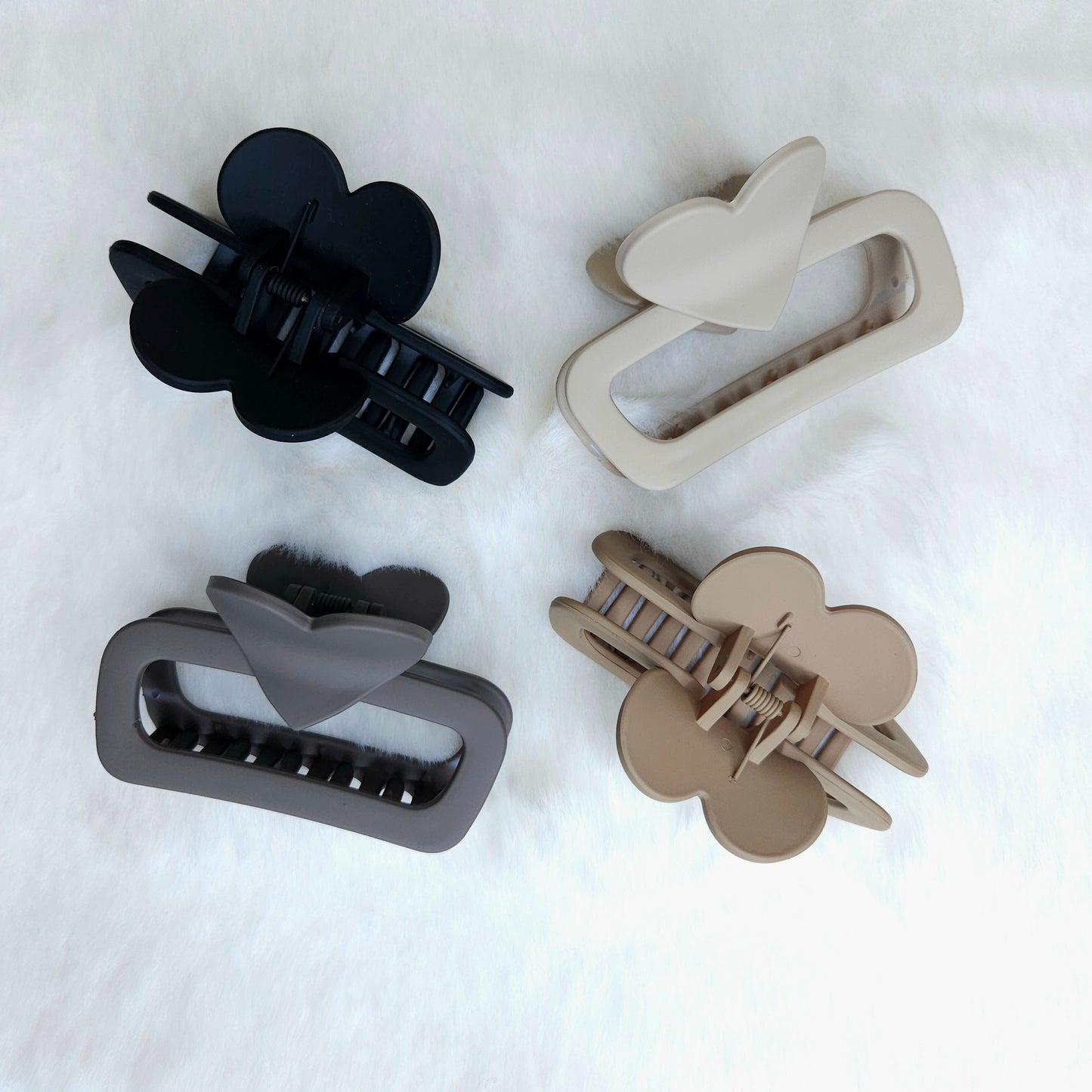 Four hair clips in black, gray, and beige on a white background
