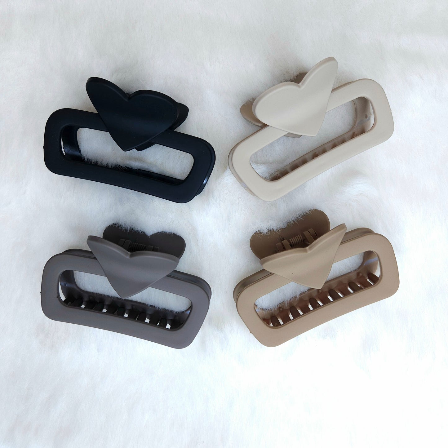 Four hair clips in black, gray, and beige on a white background