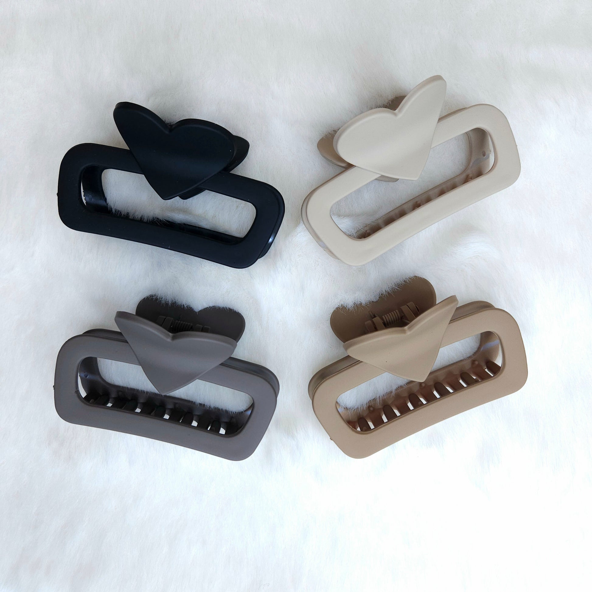 Four hair clips in black, gray, and beige on a white background